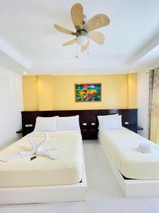 um quarto com duas camas e um ventilador de teto em Alice in Wonderland Beach Hotel em Boracay