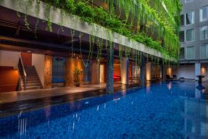 una piscina de hotel con plantas al lado de un edificio en Hotel Daun Bali Seminyak, en Seminyak