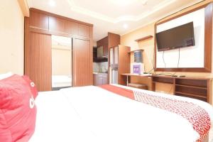 a bedroom with a bed with a tv and a bed at OYO 93545 Gateway Cicadas Apartment By Barbie Homestay in Bandung