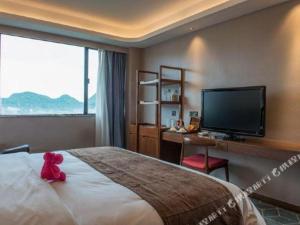 a teddy bear sitting on a bed in a hotel room at Guilin Plaza Hotel in Guilin