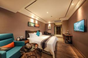 a hotel room with a bed and a blue couch at Mandolin Intelligent Hotel Jinagmen in Jiangmen
