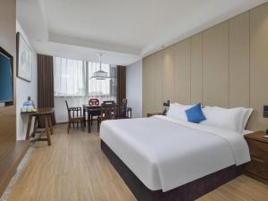 a hotel room with a large white bed and a table at GME Taizhou Jingjiang City Bus Station Hotel in Jingjiang