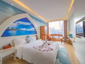 a bedroom with a white bed with a large window at Huangma Holiday Nanhai Museum Hotel in Haikou +263 photos