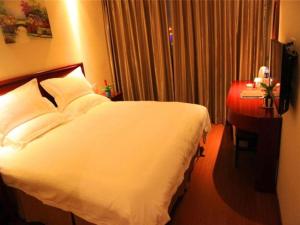 une chambre d'hôtel avec un lit blanc et une table dans l'établissement GreenTree Inn Liaoning Shenyang Tiexi Yunfeng Street Express Hotel, à Shenyang