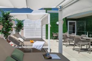 Un patio al aire libre con mesas, sillas y una sombrilla. en Ópera Apartments Alameda, en Sevilla