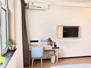 a room with a desk with a tv and a chair at GreenTree Inn Lvliang Wenshui Zetian Street Shell Hotel in Yi'er