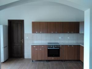 an empty kitchen with wooden cabinets and a refrigerator at Ezüstfenyő Agroturisztikai Panzió in Borzont