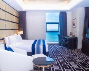 a hotel room with a bed and a desk and a window at Brigh Radiance Hotel Yantai in Yantai