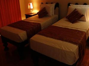 twee bedden in een hotelkamer naast een lamp bij Hotel Lans in Aswalapitiya +9 foto's
