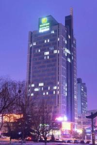 Un edificio alto con un cartel encima. en Holiday Inn Express Jinan Exhibition Center By IHG, en Jinan