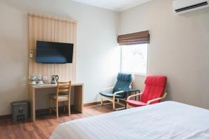 a hotel room with two chairs and a desk and a bed at Havana Mutiara Belitung in Tanjungpandan