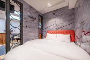 a bedroom with a white bed and a stone wall at Hotel S Shinchon in Seoul