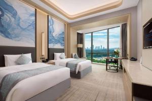 a hotel room with two beds and a large window at Howard Johnson by Wyndham Caexpo Plaza Nanning in Nanning