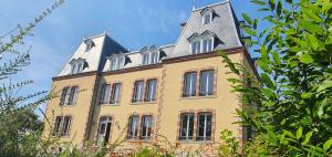 a large yellow building with a grey roof at Château de Montmireil in Canisy