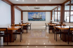ein Restaurant mit Tischen und Stühlen und einem Gemälde eines Schiffes in der Unterkunft The Sky & Sea Koh Larn in Ko Larn