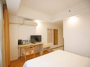 a room with a bed and a desk with a television at Anyi 158 Hotel Fuqin in Chengdu