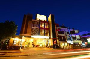 um edifício com um relógio ao lado à noite em Queen City Hotel em Bugis