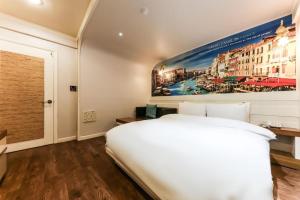 a white bed in a room with a painting on the wall at Cinema Motel in Daejeon