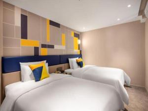 two white beds in a room with a painting on the wall at 7 Days Inn Nanchang Bayi Square Zhongshan Road Wanshou Palace in Nanchang