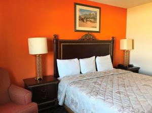 a bedroom with an orange wall with a bed and two lamps at America's Best Inn Urbana Champaign in Champaign