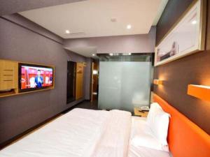 a bedroom with a bed and a tv on the wall at 7 Days Premium Qingdao Keji Street Taishan Road Metro Station in Qingdao