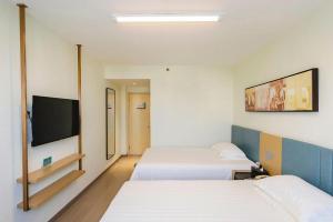 a hotel room with two beds and a flat screen tv at Jinjiang Inn Zibo People's Park Liuquan Road in Zibo