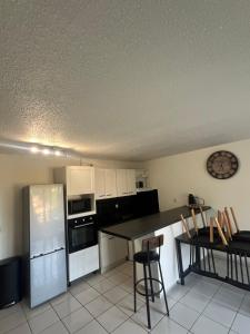 a kitchen with a refrigerator and a table with chairs at Appartement T2 proche de la plage avec parking gratuit in Canet-en-Roussillon