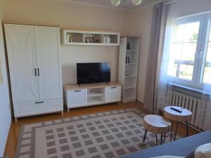 a living room with a tv and a white cabinet at Podlaska chata in Augustów