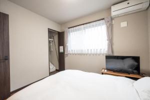 a bedroom with a bed and a flat screen tv at FAMILIA糀谷 in Tokyo