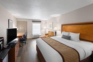 une chambre d'hôtel avec un grand lit et un bureau dans l'établissement Baymont by Wyndham Knoxville I-75, à Knoxville