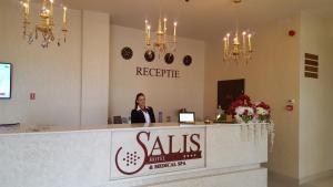una donna in piedi alla reception in un salone di Salis Hotel & Medical Spa a Turda