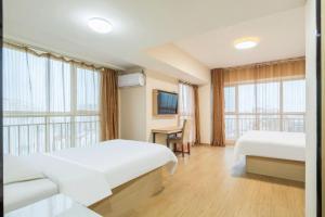 a hotel room with two beds and a television at GreenTree Inn Weihai Liugongdao Wharf Qingdao North Road Express Hotel in Weihai