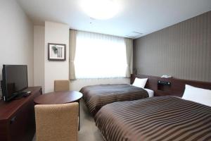 a hotel room with two beds and a television at Hotel Ligare Kasugano in Nara