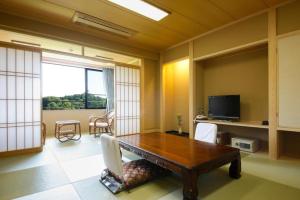 a living room with a wooden table and a television at Shigisan Kanko Hotel in Sango
