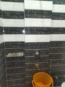 a black and white tiled bathroom with an orange bucket at Lala chuuni lal seva sadan in Rīngas