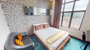 a bedroom with a bed and a chair and a window at Paragon City Hotel in Kampong Simee
