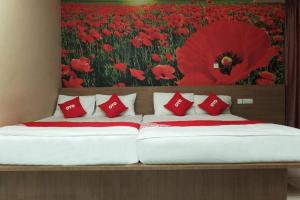 a bed with red pillows and a painting of a poppy at Super OYO 89930 Golden Guest House in Kampong Bukit Ubi