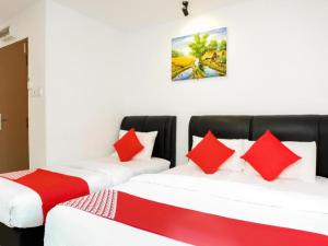 two beds in a room with red and white pillows at OYO 718 Mr J Hotel Wakaf Che Yeh 1 in Wakaf Che Yeh +205 photos