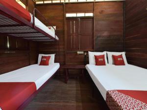 two beds in a room with red and white pillows at OYO 90630 Mat Leon Village in Kuala Tahan