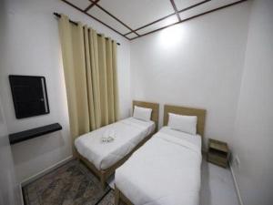 two beds in a small room with a tv at OYO 90976 Pantaistay@baturakit in Kuala Terengganu