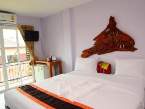 a bedroom with a white bed with a wooden headboard at Baan Taklom Chomtalay in Ban Sahakham