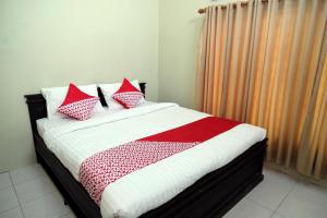 a bed with red and white blankets and pillows at Hotel O Abz Guest House Syariah in Jambi