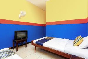 a bedroom with two beds and a tv in it at SPOT ON 2815 Hotel Damai in Cilacap