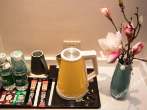 a tray with a tea kettle and a vase with flowers at Magnotel Huludao Xingcheng Central Square Wenquan Street in Huludao