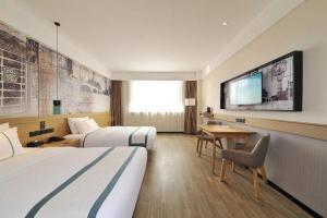 a hotel room with two beds and a desk and a tv at City Comfort lnn Dayi High-speed Railway Station in Chengdu