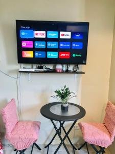 a table with two pink chairs and a tv at Cityscape Grand Tower Condo, studio unit in Cebu City