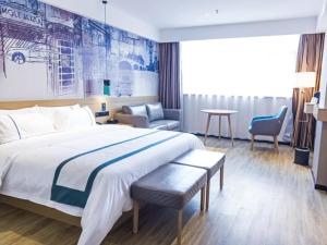 une chambre d'hôtel avec un grand lit et une chaise dans l'établissement City Comfort Inn Jingzhou Gongan Chengshi Square, à Gong'an