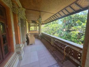a balcony of a house with a bench and a window at Rambutan Hotel in Lovina