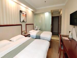 a hotel room with three beds and a flat screen tv at GreenTree Inn Zhenjiang Center Street No.1 Peoples Hospital Express Hotel in Zhenjiang