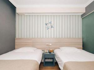 deux lits dans une chambre avec une table de chevet dans l'établissement GreenTree Inn Zhenjiang Center Street No.1 Peoples Hospital Express Hotel, à Zhenjiang 157 autres photos